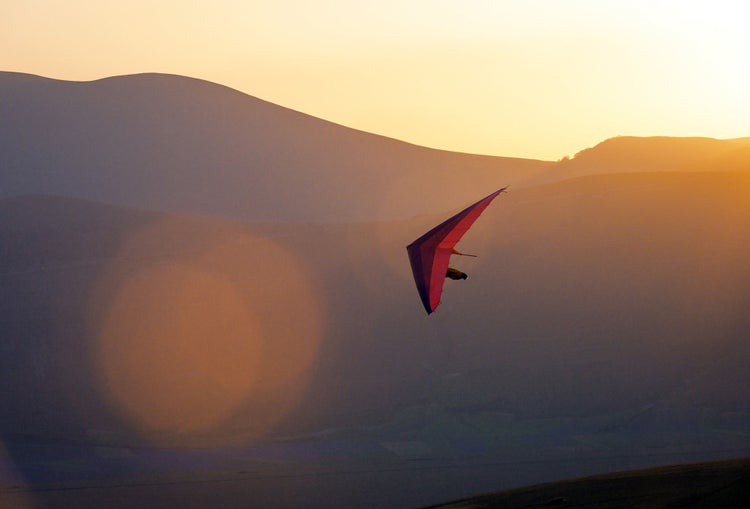 An ultralight plane against sunset sky ,hang Glider Pilot Launching,lens flare,Castelluccio,Apennines,Italy,Nikon D3x